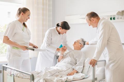 Für uns zählt der Mensch in allem, was wir tun. Arzt und Pflege am Patientenbett im Krankenhaus St. Joseph-Stift Dresden.