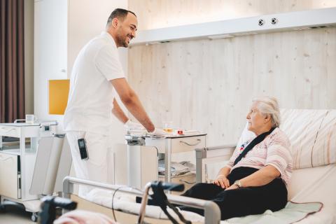Reinigung des Patientenzimmers: Reinigungskraft und Patientin im Gespräch
