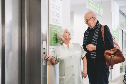 Ehrenamtliche Damen und Herren unterstützen die Patienten am St. Joseph-Stift – am Fahrstuhl.