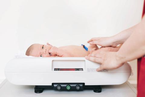 Ein Neugeborenes liegt auf der Babywaage im Kreißsaal.