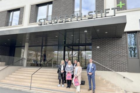 Begrüßung der finnischen Delegation einer Berufsschule aus Tampere im St. Joseph-Stift: Vertreterinnen der Schule und Geschäftsführer Viktor Helmers vor dem Eingang der Zentralambulanz.