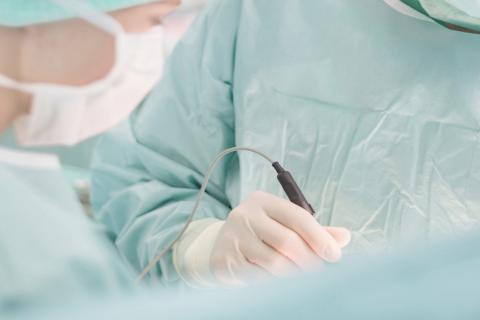 Detailaufnahme während einer chirurgischen Operation: Hände in OP-Handschuhen mit chirurgischen Instrumenten.