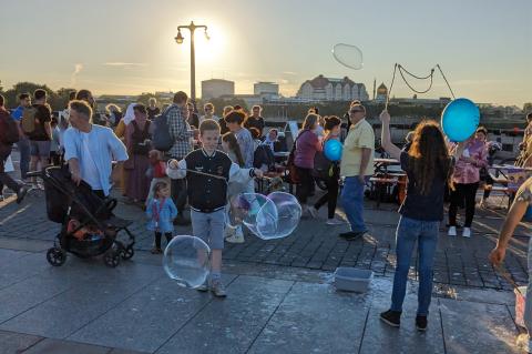Beim Gastmahl Dresden 2023 auf der Augustusbrücke: Menschen, Tische, Seifenblasen im Abendlicht.