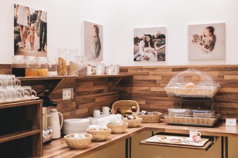 Frühstücksbuffet auf der Wochenstation der Geburtsklinik: Brot und Brötchen, Körbe mit Frühstückszutaten, Obst, Gemüse und Getränke im Bild.