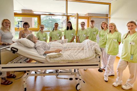 Praxisanleiterin zeigt die Lagerung von Patienten im Pflegebett.