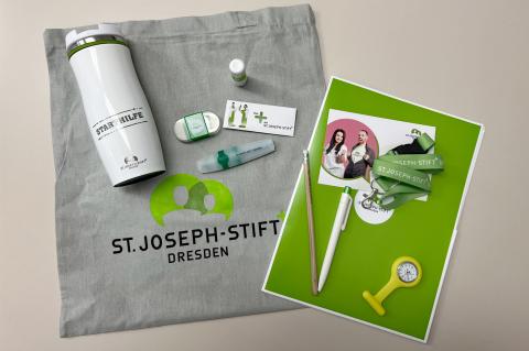 Starthilfe im Stoffbeutel: Praktische Geschenke erleichtern das Ankommen. Zum Starthilfe-Set gehören Beutel, To-Go-Becher, Stifte und weitere nützliche Dinge.