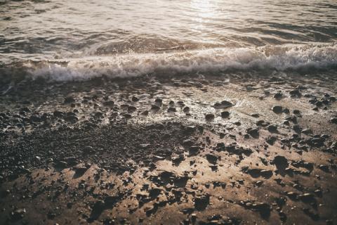 Bild Impression Meereswellen am steinigen Strand. Image für Schmerztherapie und ganzheitliche Behandlung im Zentrum.
