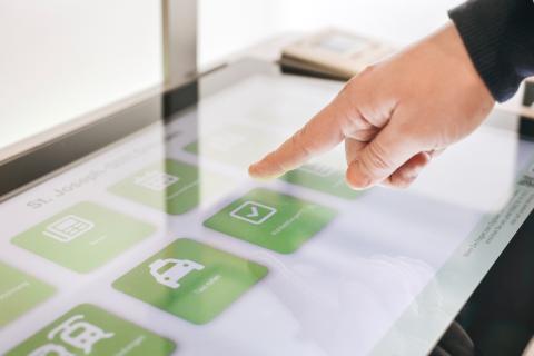 Screen mit Hand zur Visualisierung der unkomplizierten Bedienung der neuen Gesundheitsterminals am St. Joseph-Stift.
