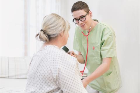 Pfleger und Patientin bei Prüfung der Vitalwerte.