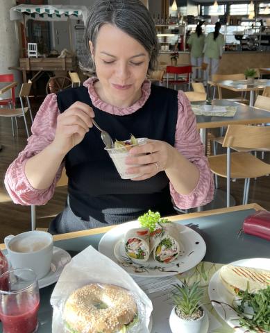 Frühstück in der Cafeteria im St. Joseph-Stift: Kollegin am Frühstückstisch mit Kaffee, Smoothie, Lachsbagel und Bircher-Müsli.