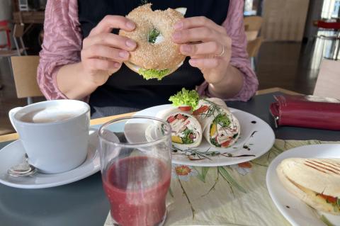 Frühstück in der Cafeteria im St. Joseph-Stift: Kollegin am Frühstückstisch mit Kaffee, Smoothie, Lachsbagel und Bircher-Müsli.