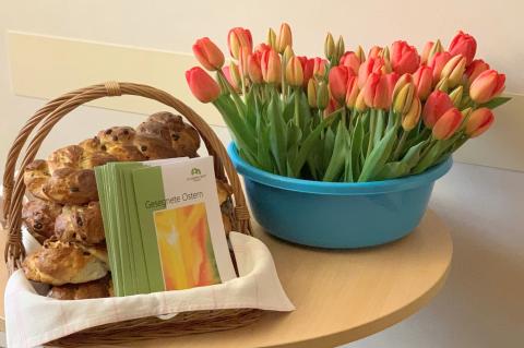 Ostern 2025: Tulpen, ein Korb mit Osterbroten und Ostergrüßen als Beiblatt auf dem Krankenhausflur.