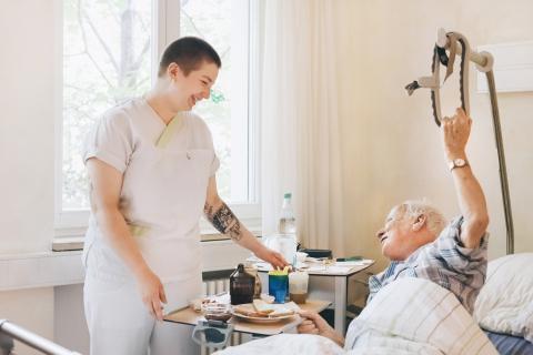 Pflegerische Zuwendung auf der Palliativstation im St. Joseph-Stift: Eine Schwester stellt dem bettlägerigen Patienten das Essen an das Bett.