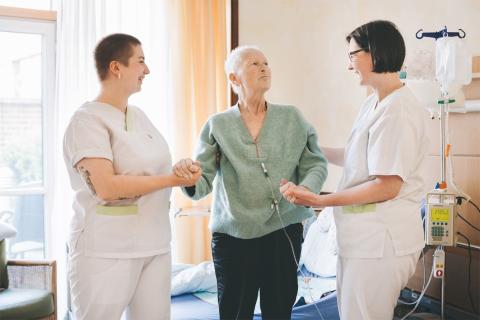 Versorgung schwerstkranker und sterbender menschen an ihrem Lebensende: Ein Behandlungsschwerpunkt am St. Joseph-Stift. Bild von der Palliativstation: zwei Pflegerinnen unterstützen Patientin beim Aufstehen.