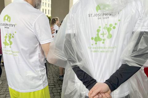 Start im Regen: Laufshirts mit SJS-Logo und Regencape zum Start bei der REWE Team-Challenge 2025.