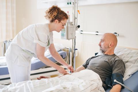 Schmerztherapie im St. Joseph-Stift – Schwester beim Anlegen einer Flexüle für Schmerzmedikation, Patient im Bett. 