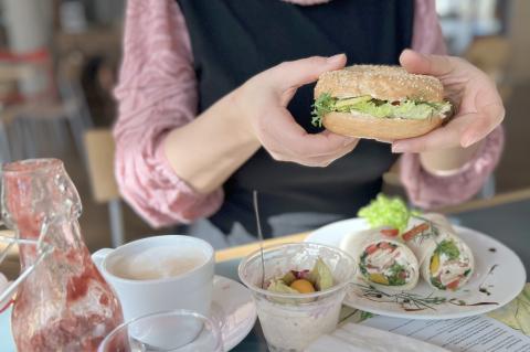 Frühstück in der Cafeteria im St. Joseph-Stift: Kollegin am Frühstückstisch mit Kaffee, Smoothie, Lachsbagel und Bircher-Müsli.