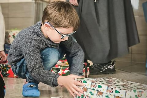 Weihnachten verschenken: Junge mit Geschenk beim Auspacken.