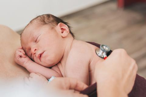 Geboren im St. Joseph-Stift Dresden: Baby kurz nach der Geburt im Bonding bei der Mama, zu sehen ist ein Stethoskop, mit dem das Neugeborene abgehört wird – auch die medizinische Erstuntersuchung findet nach Möglichkeit direkt im Bonding statt.
