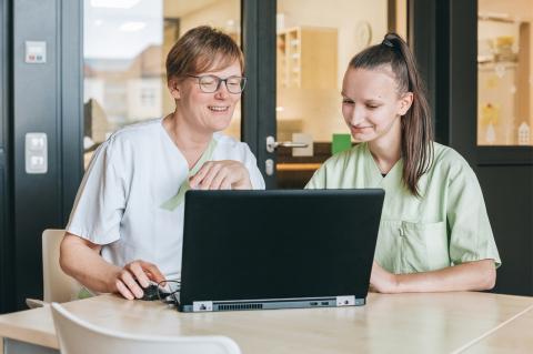 Pflegeausbildung am St. Joseph-Stift: Einblick in die Dokumentation. Lehrperson und Schülerin vor dem Laptop im Stationszimmer.