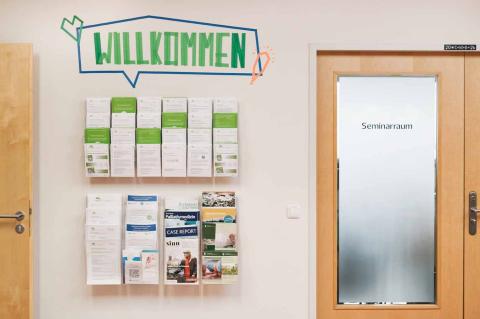 Akademie für Palliativmedizin und Hospizarbeit, Eingangsbereich, Schriftzug Willkommen oberhalb der Flyerwand.