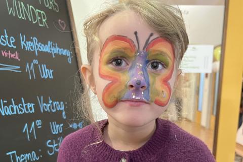Tag der offenen Tür in der Geburtshilfe 2026 – Ein Geschwisterkind posiert frisch nach dem Kinderschminken vor der Eingangstafel im Foyer.